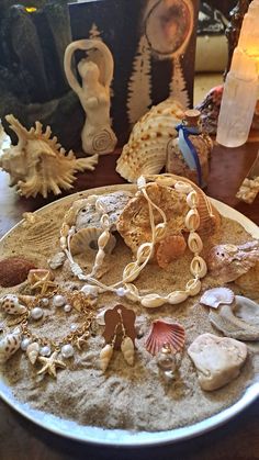 shells and seashells sit on a plate next to candles, figurines and other decorative items