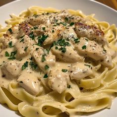 a white plate topped with pasta covered in chicken