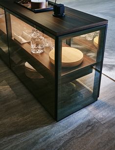 a glass cabinet with plates and glasses in it sitting on the floor next to a table