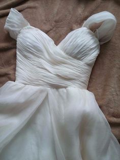 a white dress laying on top of a bed