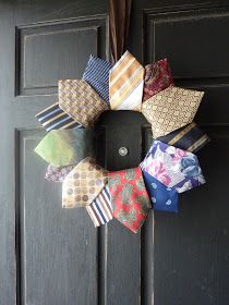 a wreath made out of ties hanging on the front door's black painted doors