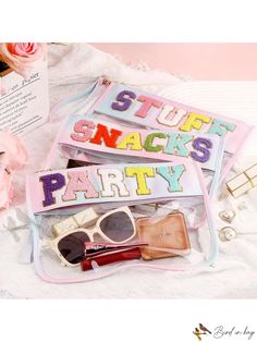 two bags filled with makeup and accessories sitting on top of a white bed next to flowers