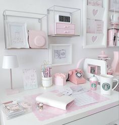 a white desk topped with lots of pink items and pictures on it's wall