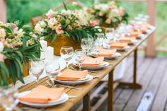 a long table set with place settings and flowers