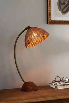 a wooden table with a lamp and some books on it next to a pair of glasses