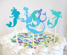 there is a cake with three mermaids on it