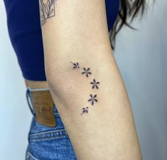 a woman's arm with small flowers on the left side of her arm and an arrow in the middle