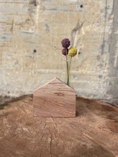 a small wooden house shaped vase with flowers in it