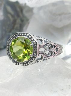 Natural Peridot RingNew Vic Design#D11 Inspired by Victorian and Edwardian designs, this stunning antique reproduction ring is crafted in white gold. This gorgeous ring is set with a flawless round natural peridot. The stunning gemstone is 8mm in diameter. The band is marked 925 (sterling silver),10k or 14k as chosen. Notice the beautifully intricate design of the silver filigree setting and band. The delicate swirl filigree craftsmanship travels down the band and morphs into angular accents. Th Classic Peridot Jewelry With Prong Setting, Classic Peridot Jewelry With Accent Stones, Antique Green Rings With Prong Setting, Classic Peridot Ring Jewelry, Green Promise Ring With Intricate Design, Green Rings With Intricate Design For Promise, Classic Peridot Green Rings, Heirloom Green Ring With Accent Stones, Heirloom Green Rings With Accent Stones