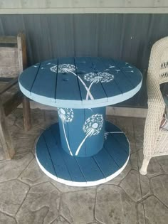 a blue table sitting on top of a wooden floor next to a wicker chair