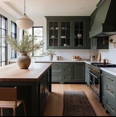 a kitchen with green cabinets and white counter tops, an area rug on the floor