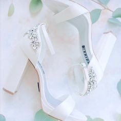 a pair of white high heeled shoes sitting on top of a flowery table