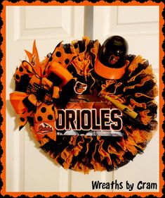 an orange and black wreath with the word orioles on it is hanging from a door