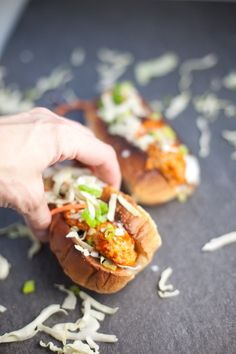 two hot dogs on buns with toppings being held by someone's hand