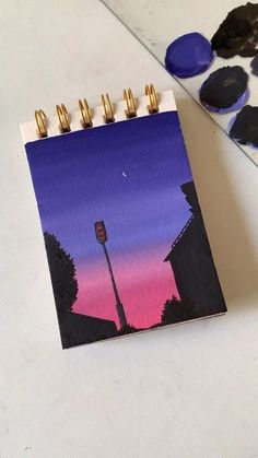 a notepad with a painting of a street light on it next to some paint chips