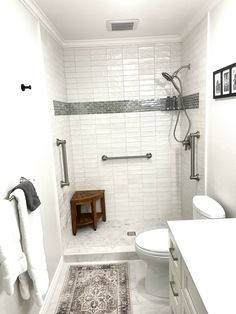 a bathroom with a toilet, sink and shower in it's stall area that has a rug on the floor