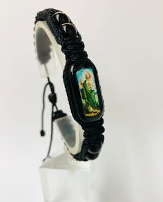 "Pulsera de San Judas Tadeo hecha a mano de doble tejido estilo Macrame con hilo reforzado en color negro. San Judas Tadeo el patrono de caso imposible. Pulsera ajustable y expandible para hombre o mujer con minimo cierre de 7\" pulgadas hasta maximo de 9\" pulgadas. Tableta de madera (1\"x 1/2\" x 1/4\" ) color verde obscuro con imagen de alta definicion San Judas en ambos lados y cubierta con resina Hilo reforzado #18 color Negro Bolas gemstone Onyx negro 8mm Nudo: 12" Black Woven Braided Bracelets For Gift, Black Woven Braided Bracelets As Gift, Black Woven Braided Bracelet For Gifts, Black Braided Bracelets As Gift, Adjustable Black Woven Friendship Bracelets, Handmade Black Spiritual Friendship Bracelets, Handmade Black Braided Casual Bracelet, Handmade Black Casual Braided Bracelet, Casual Black Handmade Braided Bracelets