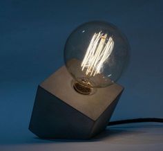 a light bulb sitting on top of a wooden block with a wire coming out of it