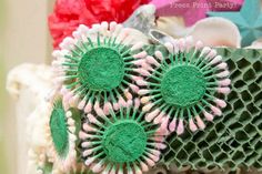 three green and pink flowers on top of a piece of paper with holes in the middle