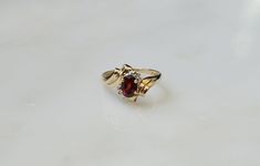 Vintage Circa 1980 Constructed of 10 Karat Yellow Gold Containing 1 Central Oval cut Genuine Earth-Mined Deep Intense Red Garnet weighing approximately 1 carat at 6.4mm in length x 4.6mm in width Secured in a 4-Prong Setting *Garnet is the birthstone for those born in January..  Accented with 2 Round Brilliant cut Genuine Earth-Mined Diamonds weighing a total of approximately 0.03 carats  ranking a 'Nearly Colorless' F-G Color & I1 Clarity --Shown on a Woman's Finger Size 6.5 in the natural dayl Oval Yellow Gold Bypass Ring For Formal Occasions, Oval Ruby Ring Stamped 14k For Anniversary, Oval Ruby Ring For Anniversary Stamped 14k, Vintage Oval Birthstone Ring For Formal Occasions, Collectible Oval 14k Gold Rings, Oval 14k Gold Rings For Collectors, Vintage Oval Birthstone Diamond Ring, Collectible 14k Gold Oval Rings, Formal Oval Birthstone Ring Stamped 14k