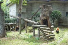 an animal that is standing in the grass near some trees and stairs with a building behind it