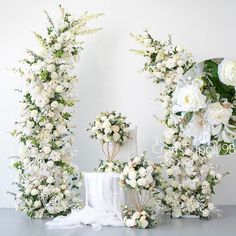 white flowers and greenery are arranged in the shape of letters