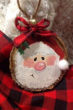 a christmas ornament hanging from a tree slice with a santa clause on it