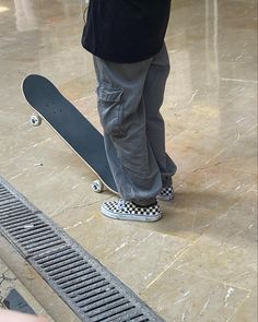 a person standing on top of a skateboard next to a drain grate in a building