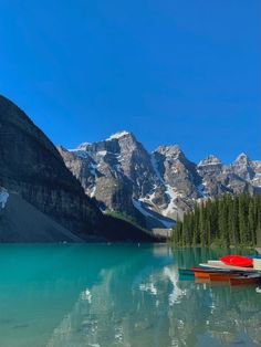 three canoes sitting on the shore of a mountain lake