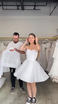 a man standing next to a woman in a white dress holding a piece of cloth