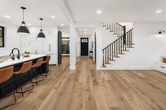 an open floor plan with white walls and wood floors, two staircases leading up to the second floor