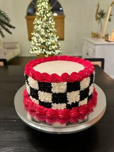 a red and black cake sitting on top of a table next to a christmas tree