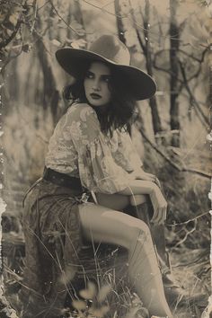 an old photo of a woman wearing a hat and sitting in the woods with her legs crossed