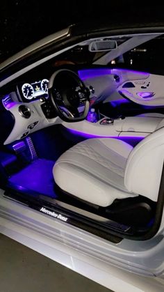 the interior of a car is lit up with blue lights and white leather seats,