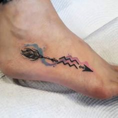 a tattoo on the foot of a person with an arrow and watercolor splashes