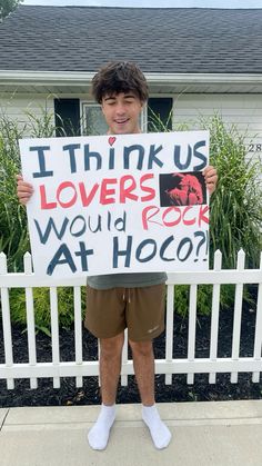 a young man holding up a sign that says i think us lovers would rock at hoo?