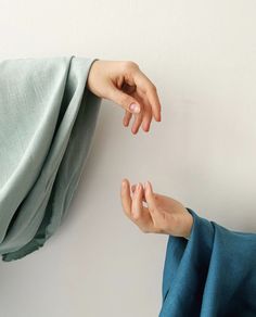 two hands reaching for each other on a white wall with blue fabric draped over it