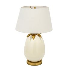 a table lamp with a white shade and gold trimmings on the bottom half