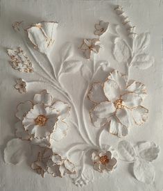 an artistically designed piece of white paper with gold foiled flowers and leaves on it