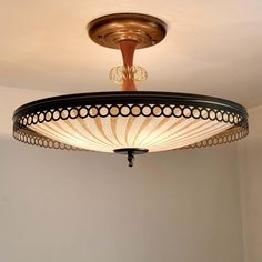 a ceiling light with an intricate design hanging from it's center point in a room