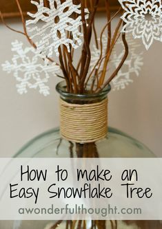 an easy snowflake tree in a glass vase with twine and paper snowflakes