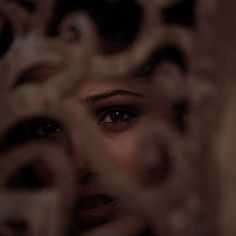 a woman's face is seen through a decorative screen