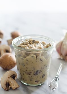 a jar filled with food sitting on top of a counter next to garlic and mushrooms