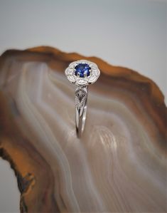 CJ71782SPH Vintage inspired sapphire-diamond 14k gold ring. This is a gorgeous 14k white gold flower halo ring with a migraine design. Eight round diamonds are set around the halo with a beautiful genuine blue sapphire set in the center. Sapphire is .44cts, approximately 4.5mm. Diamonds are .06cts in total weight. Halo measures approximately 9mm. Currently the ring is size 7 but can be resized, please inquire. Sapphire Halo Ring In 14k White Gold, Silver Sapphire Ring With Halo Detail, Sapphire Diamond Cluster Ring With Halo Design, Sapphire Cluster Ring With Halo For Anniversary, Sapphire Cluster Ring With Halo For Promise, 14k White Gold Gia Certified Halo Promise Ring, Sapphire Halo Ring For Promise Occasion, Gia Certified 14k White Gold Halo Promise Ring, Gia Certified Silver Sapphire Halo Ring