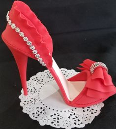 a red high heeled shoe on top of a doily