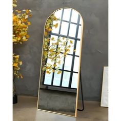 a large mirror sitting on top of a table next to a vase filled with flowers