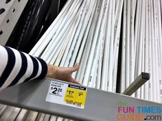 a person is pointing at some white tubes on a shelf in a store with the price tag