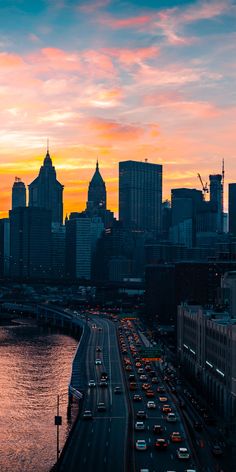 the city skyline is lit up at sunset with traffic driving on the road in front of it