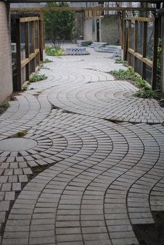 the walkway is made out of bricks and has an open gate