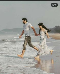 a man and woman are walking along the beach